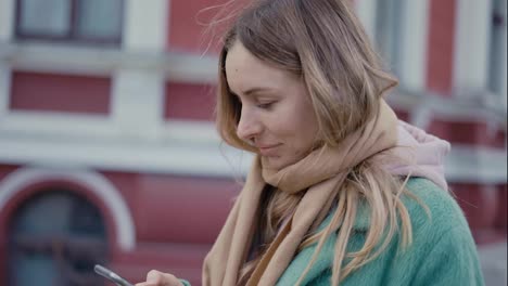 Woman-listening-to-music-wear-earphones-looking-at-smartphone-on-the-street