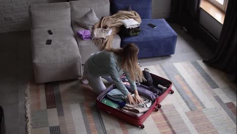 A-woman-in-a-hotel-room-puts-things-in-a-suitcase