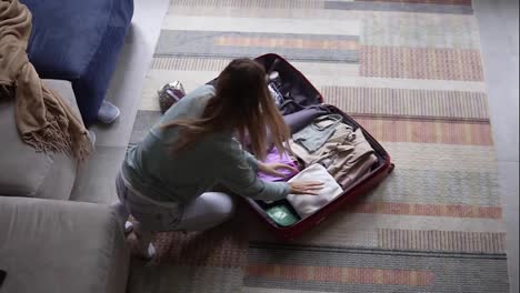 Eine-Frau-In-Einem-Hotelzimmer-Packt-Dinge-In-Einen-Koffer,-Blick-Aus-Der-Vogelperspektive