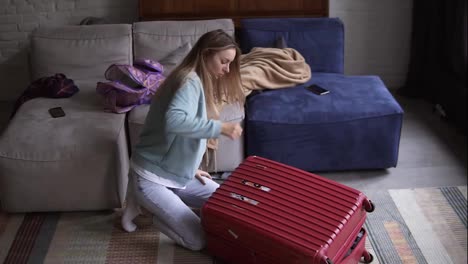 Woman-closing-and-zipping-suitcase,-getting-ready-for-road-trip-preparing-luggage-for-vacation-in-a-living-room