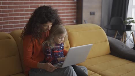 Madre-E-Hija-Sentadas-En-El-Sofá-Y-Usando-Una-Computadora-Portátil