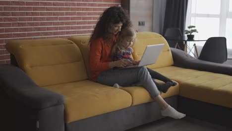 Mutter-Und-Tochter-Sitzen-Auf-Der-Couch-Und-Tippen-Auf-Dem-Laptop