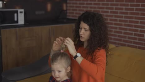 Mom-is-combing-the-blonde-hair-for-the-daughter,-making-ponytail