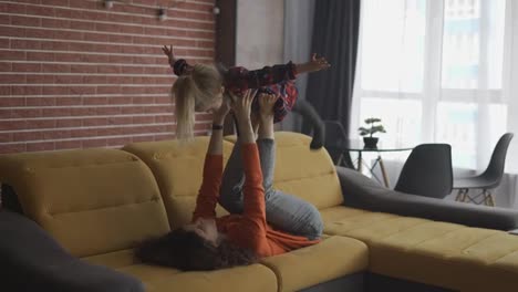 Mother-lifting-girl-in-air-on-her-ankles,-pretending-to-fly-at-home