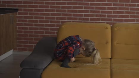 Small-girl-doing-somersault-or-forward-roll-on-sofa-at-home