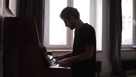 Bearded-man-professionally-play-the-piano-at-home-against-window