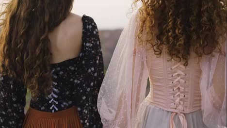 Two-curly-women-travelers-are-walking-along-a-lavender-field-in-corset-dresses
