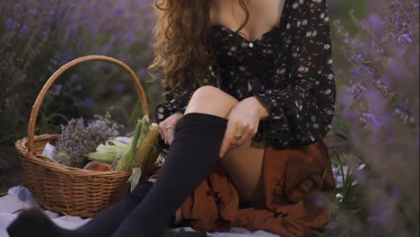 Sensual-woman-on-lavender-field,-putting-on-black-tights