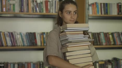 Girl-student-holding-a-lot-of-books-in-the-library,-preparing-for-exams