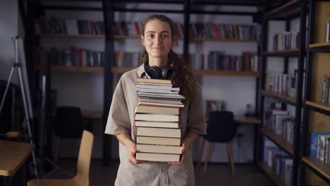 Lächelnder-Student-Hält-Viele-Bücher-In-Der-Bibliothek-Und-Bereitet-Sich-Auf-Prüfungen-Vor