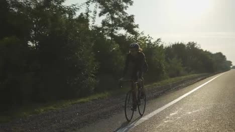 Male-cyclist-in-helmet-rides-bicycle-along-an-empty-track,-slow-motion