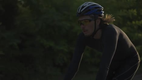 Un-Ciclista-Masculino-Con-Casco-Monta-En-Bicicleta-Y-En-Una-Pista-Vacía,-De-Cerca
