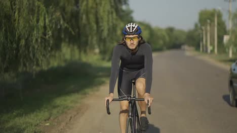 Concentrated-cyclist-in-helmet-rides-bicycle-along-the-track,-slow-motion