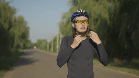 Deportista-Poniéndose-El-Casco-Y-Empezando-A-Andar-En-Bicicleta-Por-La-Carretera