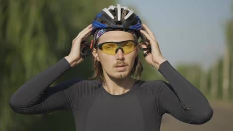 Sportsman-putting-on-his-helmet-on-a-bicycle,-close-up