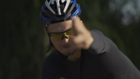 Portrait-of-a-cyclist-on-a-bike-and-showing-bang-sign-with-hand