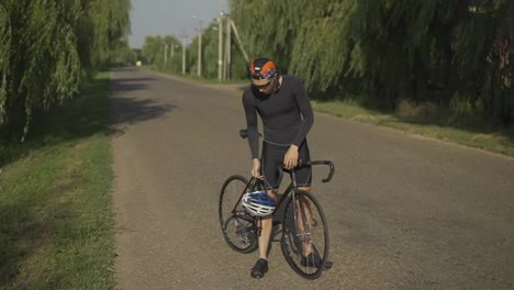 Sportsman-putting-on-his-helmet-on-a-bicycle,-full-length