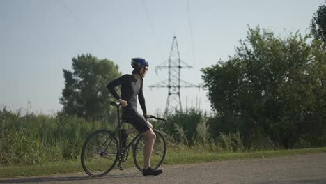 Retrato-De-Ciclista-En-La-Carretera-Vacía-Descansando-Sobre-Su-Bicicleta