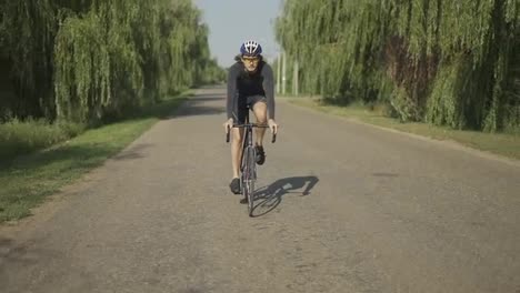 Männlicher-Radfahrer-Mit-Helm-Fährt-Fahrrad-Entlang-Der-Strecke-Und-Gewinnt-An-Geschwindigkeit,-Vorderansicht