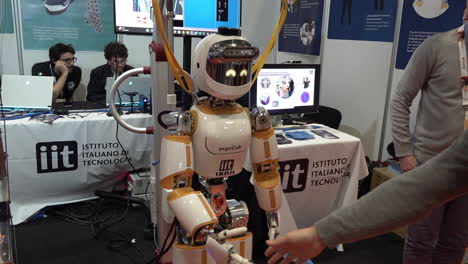 A-man-shakes-the-hand-of-a-humanoid-robot-at-the-IEEE-Robotics-and-Automation-Society-Conference-at-the-Excel-Centre