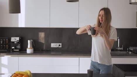 A-young-woman-is-dancing-in-the-kitchen-and-drinking-coffee