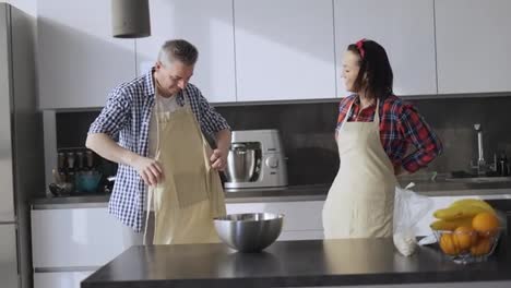 Romantic-couple-at-home-in-the-kitchen-putting-aprons