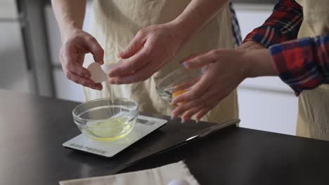 Man-and-woman-separating-egg-whites-from-yolk-into-bowl