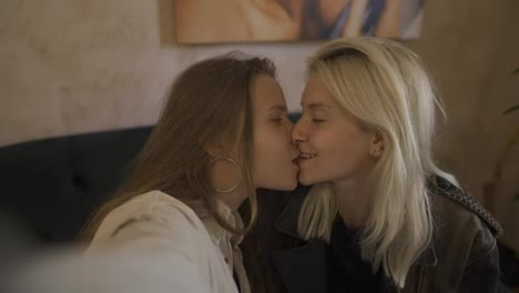 Two-affectionate-women-kissing-sensually-at-the-cafe