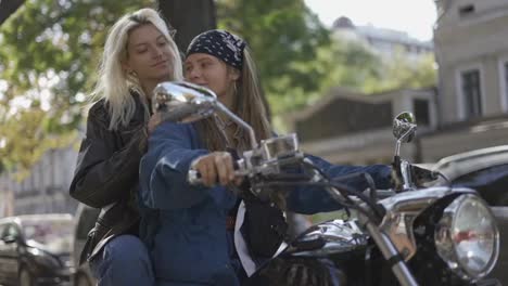 Two-beautiful-young-women-on-a-motorcycle-at-city-street