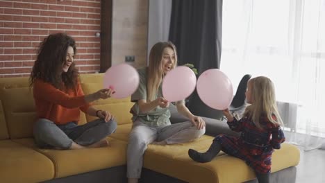 Mother-and-her-sister-are-playing-with-balloons-with-blondy-small-girl