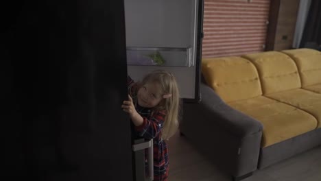 Cute-little-girl-opens-fridge-door-reaching-for-something