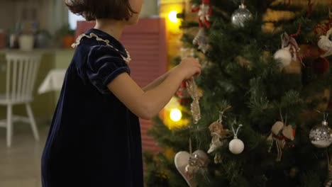 Kleines-Mädchen-Im-Kleid,-Das-Zu-Hause-Den-Weihnachtsbaum-Schmückt