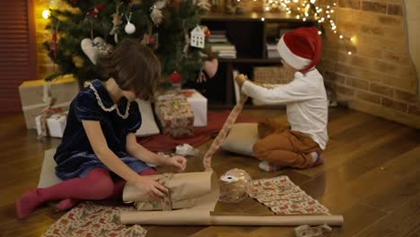 Cute-little-girl-and-her-brother-wrapping-Christmas-present