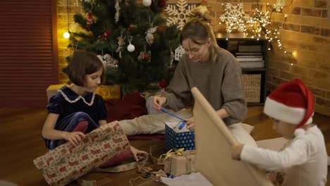 Mother-and-kids-wrapping-Christmas-present-on-the-floor