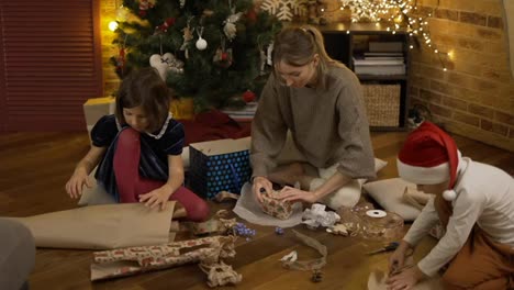 Mutter-Und-Kinder-Packen-Gemeinsam-Weihnachtsgeschenke-Auf-Dem-Boden-Ein
