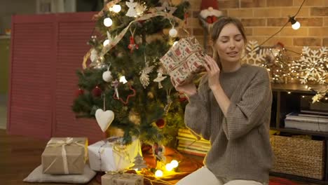 Blonde-woman-shaking-Christmas-gift-box-guessing-what-inside