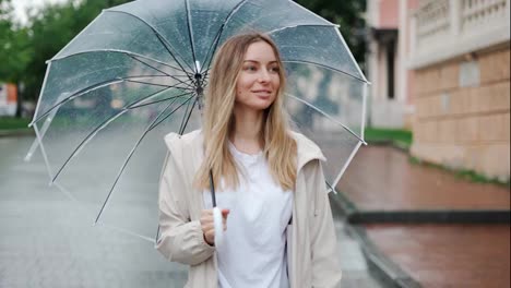 Mujer-Sonriente-Caminando-Con-Paraguas-Transparente-En-Días-De-Lluvia