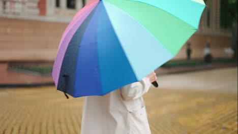 Frau-Mit-Einem-Bunten-Regenschirm,-Die-Im-Regen-Läuft