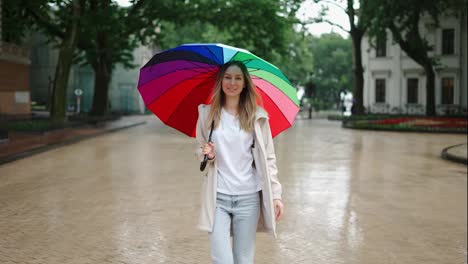 Portrait-of-a-woman-walking-by-city-street-with-multi-colored-umbrella