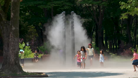 Eine-Gruppe-Von-Kindern-Kühlt-Sich-An-Heißen-Sommertagen-Unter-Einem-Beschlagenen-Micro-Flow-Tropfkühlsystem-Im-öffentlichen-Park-Yangjae-Citizen-Forest-Ab