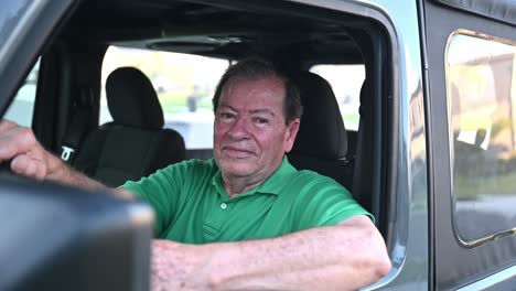 man-wearing-a-green-shirt-waving-in-his-new-car