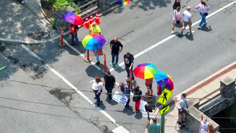 Aerial-top-down-shot-of-protesters-with-Christian-religious-signs-at-entrance-of-Lesbian-Gay-Bi-Trans-Queer-Pride-Parade-Festival-in-american-town