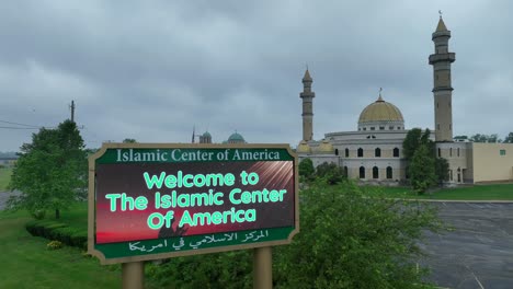 Aerial-view-showing-Welcome-to-The-Islamic-Center-of-America-digital-sign-and-mosque-building-in-Background-during-cloudy-day
