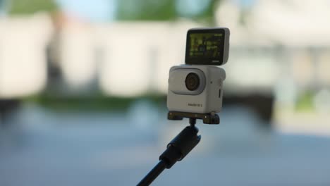 Insta360-Go-3-Being-Held-On-Selfie-Stick-Outside-With-Blurred-Background