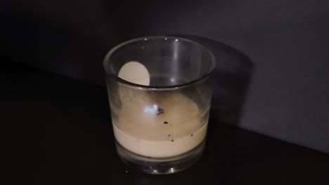 Pale-wax-candle-burning-in-a-dark-room
