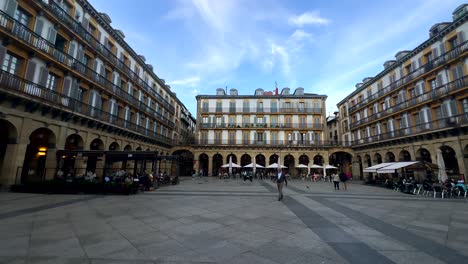 Panorama-wide-shot-showing-historic-Constitution-Square-of-San-Sebastian-with-tourist-and-people-in-restaurant---Beautiful-old-buildings-in-Spain---Panning-shot