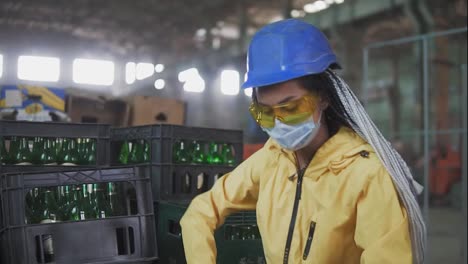 Woman-worker-in-mask-controls-the-recycle-waste-separation-of-recyclable-waste-plants.-Sorting-glass-bottles-into-boxes-for-further-disposal.-Slow-motion