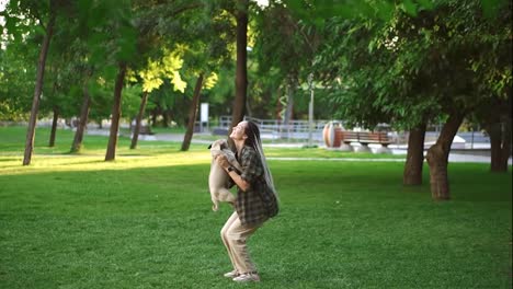 The-girl-and-pug-dog-are-having-fun,-she-throws-the-dog-in-the-air-in-the-park