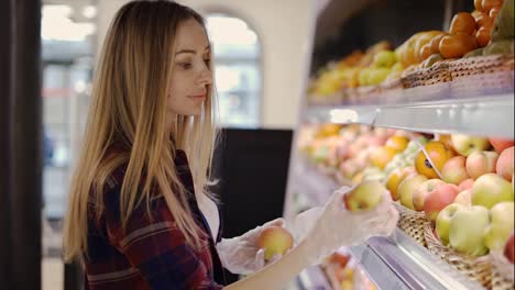 Mujer-En-Guante-Recoge-Frutas-Manzanas-En-Cesta-En-El-Supermercado