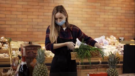 Female-worker-in-black-apron-and-mask-arranging-greens-in-supermarket,-removing-spoiled
